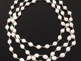 a necklace with pearls and emeralds on a black background