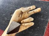 a hand that is holding a piece of wood with a knife