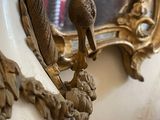 a white vase with a bird on it and a mirror in the background