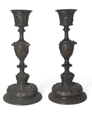 une paire de bougeoirs anciens en bronze sur socles, sur fond blanc