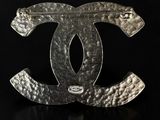 a chanel logo broocher in silver on a black background