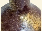 a brown vase with a gold top sitting on a table