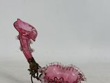 un vase en verre rose posé sur un socle en métal
