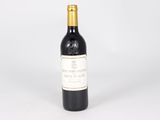 a bottle of red wine sitting on top of a white table