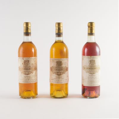 trois bouteilles de vin posées les unes à côté des autres sur une surface blanche