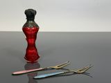 un vase rouge et une paire de ciseaux posés sur une table