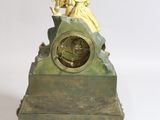 a small clock with a statue on top of it