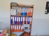 a desk with a bookcase full of binders on it