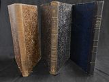 trois vieux livres sont empilés les uns sur les autres sur un fond noir