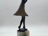 statue of a woman in a dress holding a hat on top of a marble base