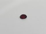 a red garnet stone sitting on top of a white surface