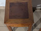 a small wooden table with a glass top on a tiled floor