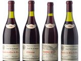 four bottles of wine are lined up on a white surface