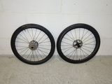 two black and white wheels are sitting against a white wall