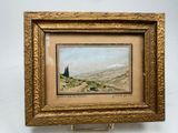 une peinture à l'huile représentant un paysage, dans un cadre doré, accrochée à un mur blanc