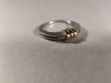 silver and gold ring on a table with a white background
