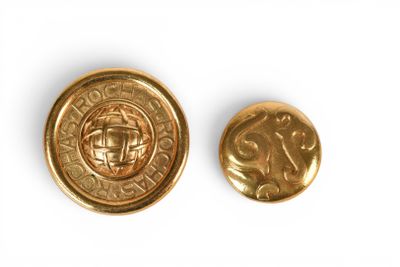 a close up of two gold colored buttons on a white surface