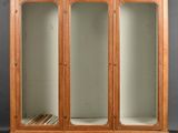 a wooden cabinet with glass doors and shelves on wheels