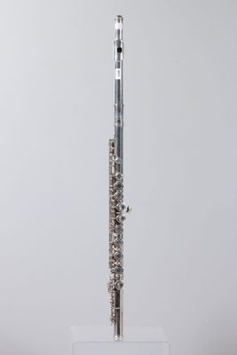 a silver flute on a clear stand against a gray background