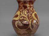 vase marron et doré orné d'un oiseau sur un fond gris