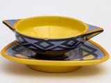 un bol jaune et bleu posé sur une soucoupe
