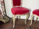 pair of red velvet chairs sitting on top of a wooden floor next to a window
