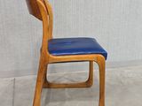 a wooden chair with a blue seat on the concrete floor
