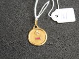 une médaille d'or suspendue à un cordon, avec une étiquette indiquant son prix