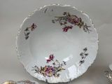 a white plate with pink flowers on it next to a silver cup and saucer