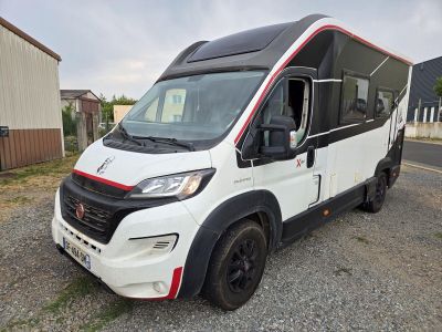 une photo d'un camping-car blanc et rouge garé sur le bord de la route