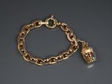 a close up of a gold chain bracelet with a bell charm