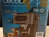 boxed coffee machine sitting on top of a wooden table next to a cup of coffee