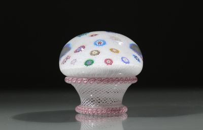 une image représentant un objet en forme de cupcake blanc et rose posé sur une surface réfléchissante