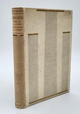un vieux livre posé sur une table à côté d'un mur blanc