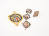 trois insignes et une épingle sont posés sur une surface blanche