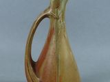 a brown and orange pitcher with a handle on a table