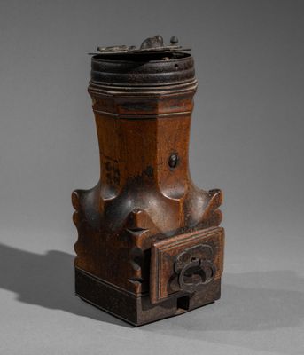 an old wooden grinder with a metal lid on a gray surface