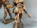 statue of two soldiers with guns on a base on a gray surface