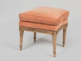 un repose-pieds rembourré de couleur orange, avec des pieds en bois et un coussin