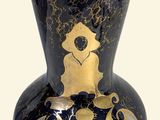 a black and gold vase sitting on a white surface