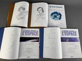 several open books with drawings of people on them sitting on a table