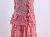 a pink dress with ruffles on a mannequin stand