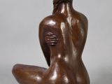 an image of a bronze statue of a woman sitting on the ground