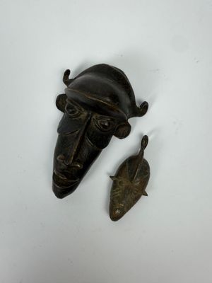 une image représentant un masque en bronze et un poisson sur un fond blanc