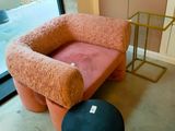 une chaise rose et un tabouret noir dans une pièce