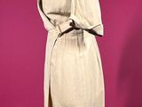 beige trench coat on a mannequin stand against a pink background