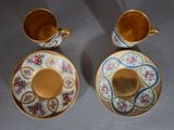 two cups and saucers are sitting side by side on a table
