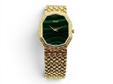 a close up of a gold watch with a green face
