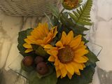 a basket with sunflowers and other flowers on a table