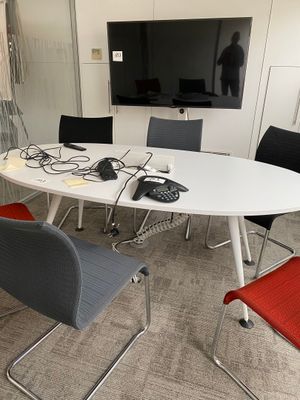 une table blanche entourée de chaises, avec une télévision accrochée au mur